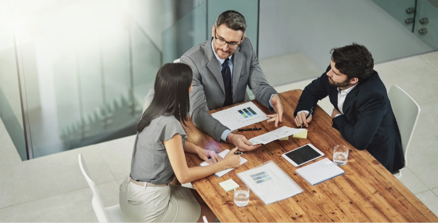 three people discussing charts at a desk