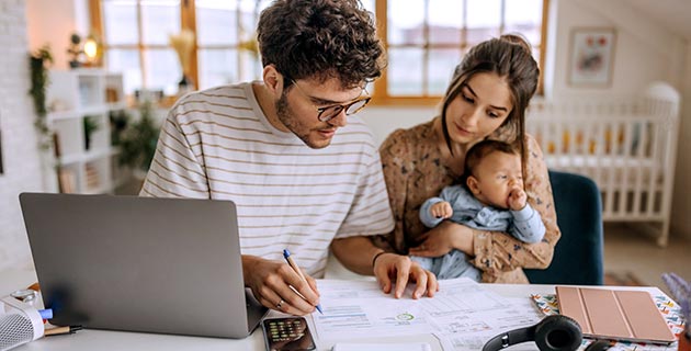 Parents and child looking at paperwork with a laptop