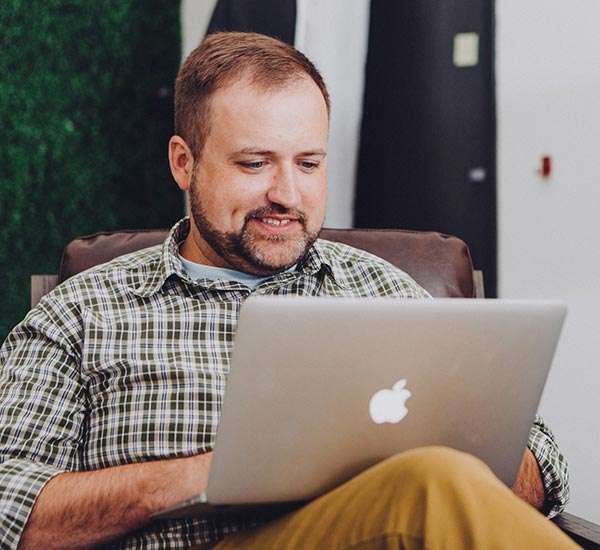 Man using laptop while sitting in a chair.