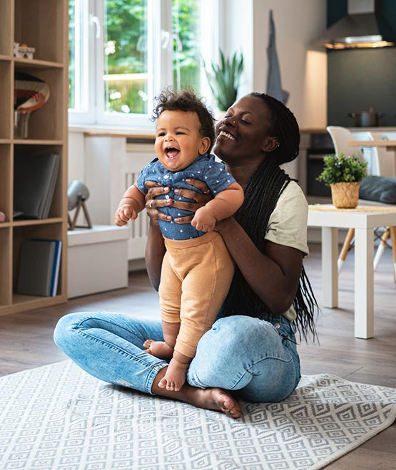Mom holding child while sitting on the floor at home.
