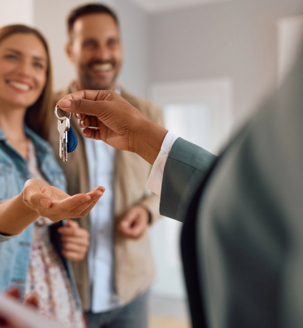 realtor handing keys to house to couple